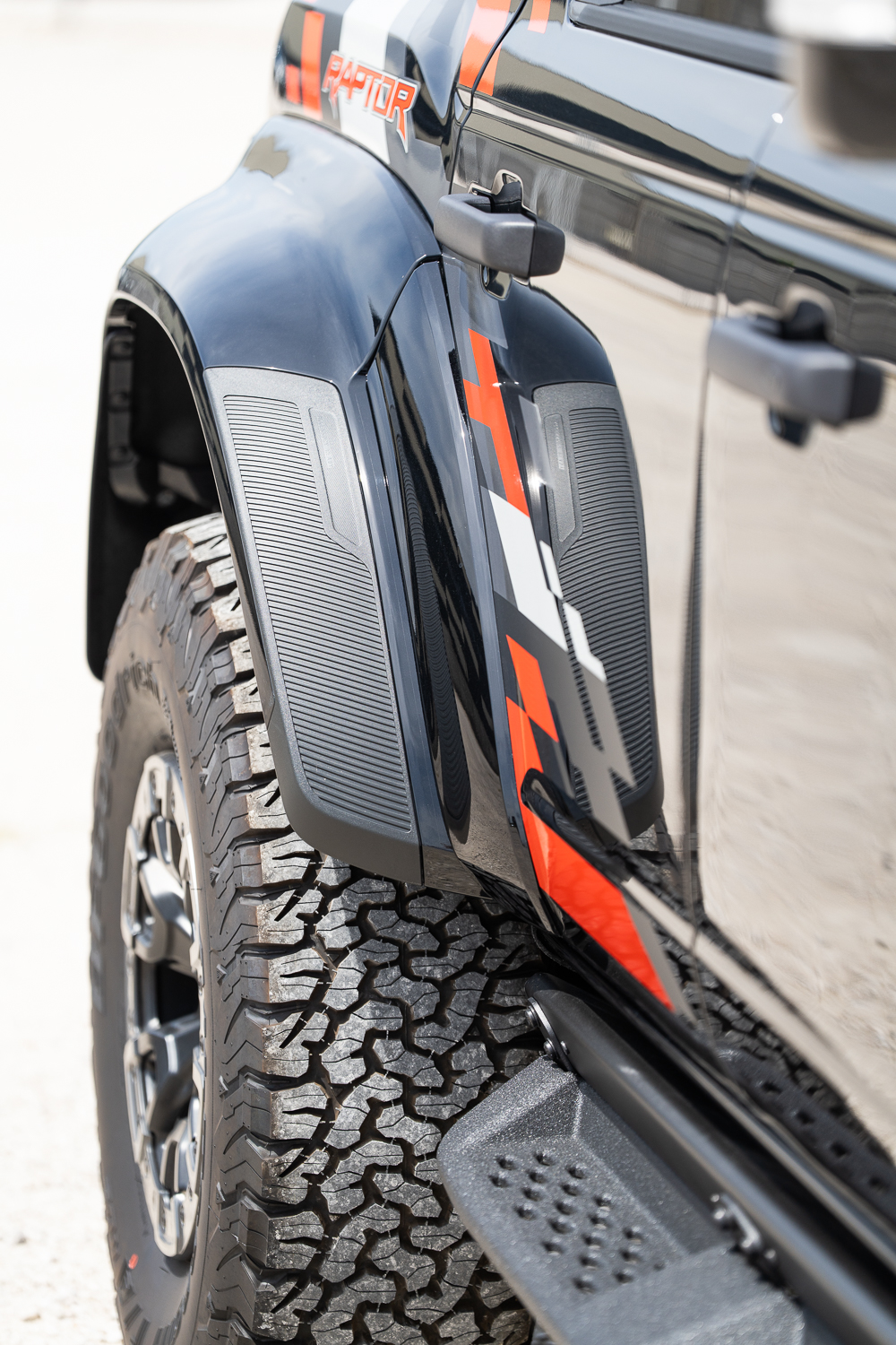 Ford Bronco Raptor hátsó sárvédőjének Code Orange grafikája és RAPTOR felirata közelről
